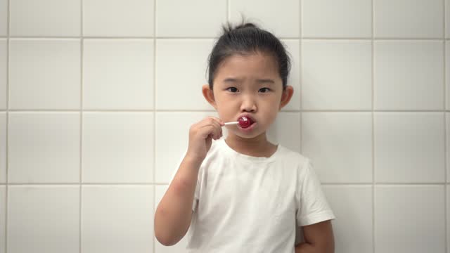Little girl brushes teeth with lollipops