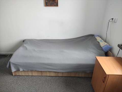 Bed in a small cozy student room in a student dormitory