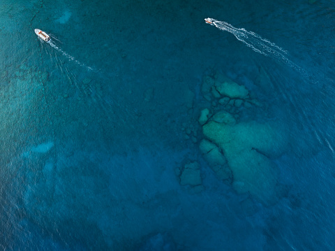 Aerial view on two ships cruising above the heart shaped rock in the sea (Crete, Greece).