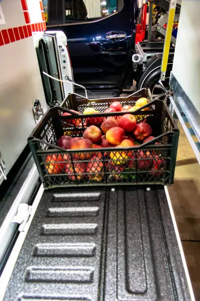 Red apples in a plastic box on a mini cargo van