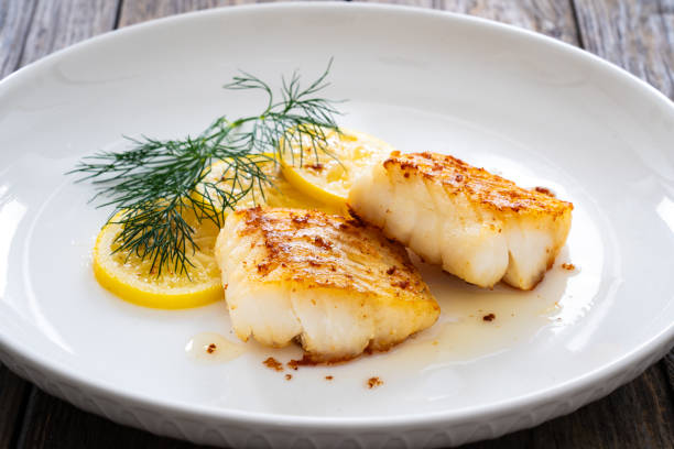 istock Fried codfish loin, lemon slices and dill on wooden table 2099160761