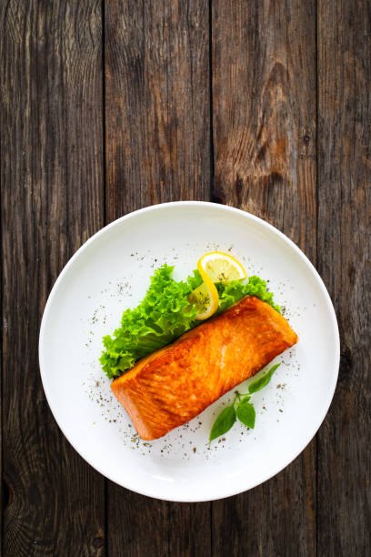istock Seared salmon steak with fresh vegetables on wooden table 2099165654