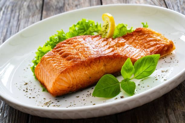 istock Seared salmon steak with fresh vegetables on wooden table 2099166728