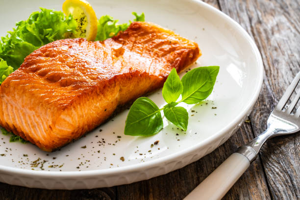 istock Seared salmon steak with fresh vegetables on wooden table 2099167270