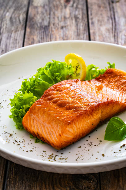 istock Seared salmon steak with fresh vegetables on wooden table 2099167834