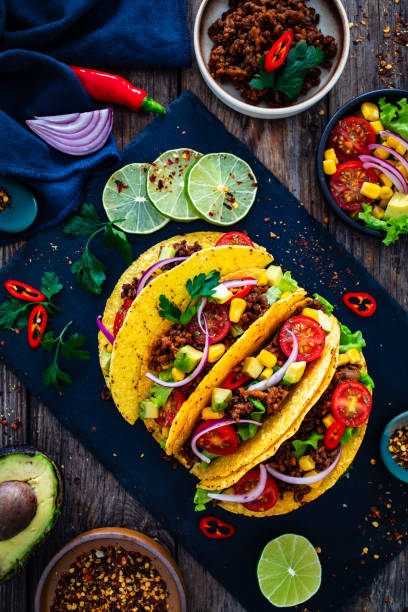 istock Tacos with ground beef, avocado, corn and fresh vegetables on wooden table 2099175351