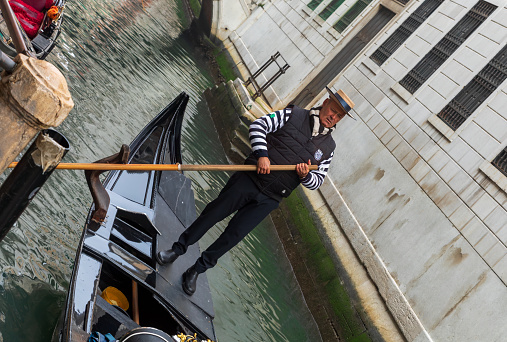 Image of a Gondola carrying being punted by its gondolier along one of the canals in Venice