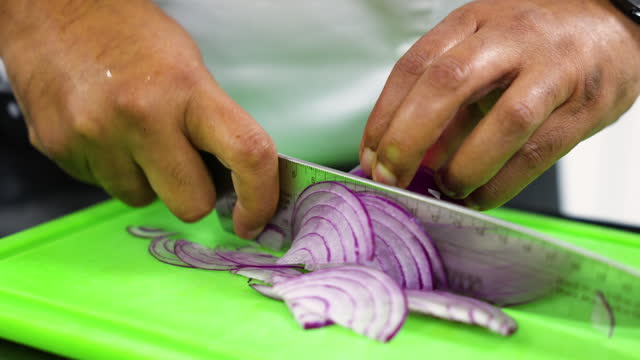 Unrecognizable chef slicing a red onion at the restaurant