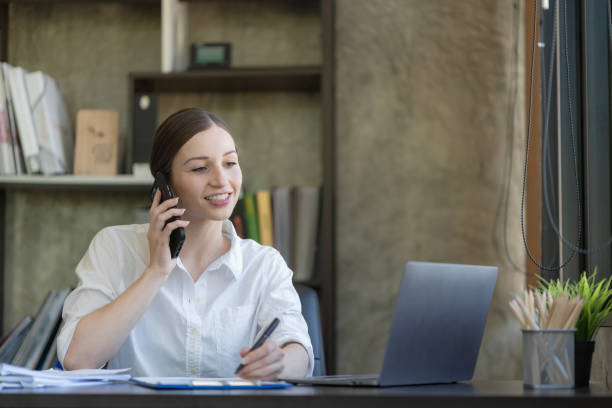 istock Happy businesswoman using a mobile phone while sitting in an office. 2099214679