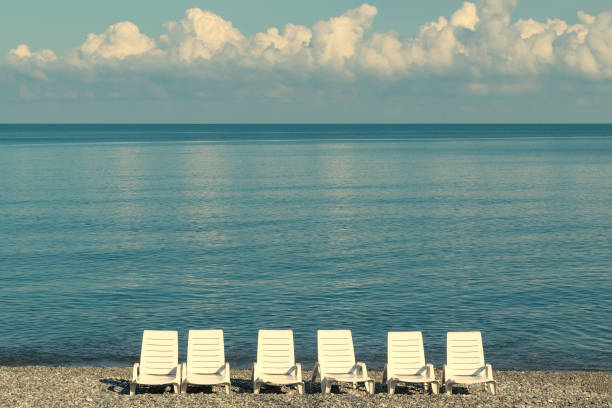 White sunbeds on the seashore. Holidays at sea. Marine landscape.