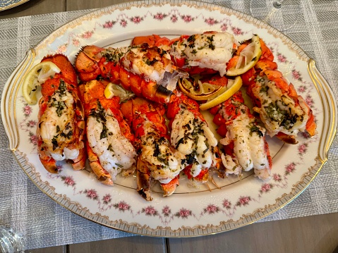 Photo of cooked delicious lobster tails displayed on an ornate platter on a table