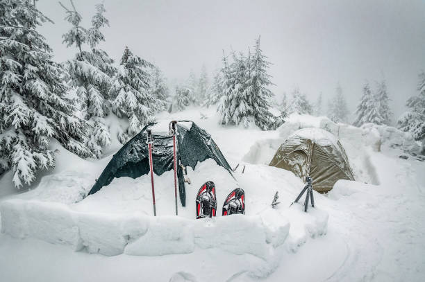 Camp in winter mountains, two tents in snowdrift. Winter sport and recreation