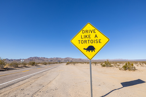 A yellow speed warning sign on the side of the road in a desert area in California, western USA