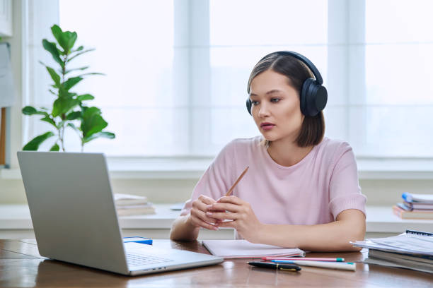 istock Young female college student in headphones studying using laptop computer for video chat 2099278105