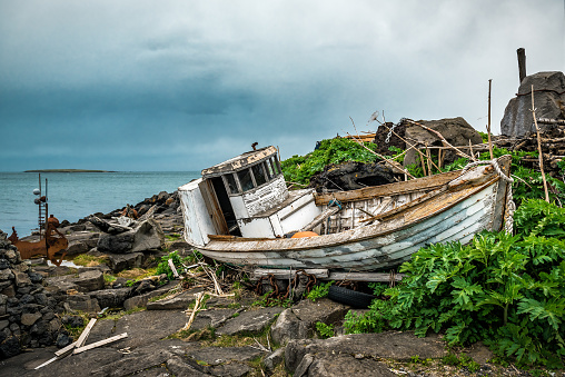 Old boat wreck on the shore near recycled house in Reykjavik, Iceland