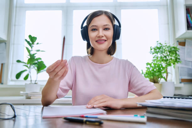Webcam portrait of young female student wearing headphones, sitting at home at desk Webcam portrait of young 20s female student wearing headphones, sitting at home at desk, looking at camera, talking. Internet online webinar, video chat call conference, technology education training online tutors stock pictures, royalty-free photos & images