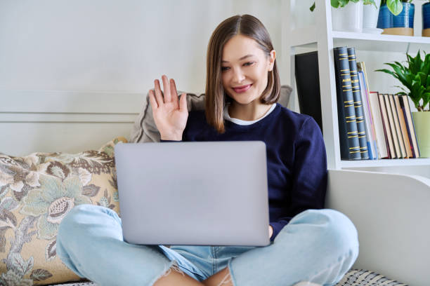 istock Young woman using laptop sitting on sofa at home 2099286797