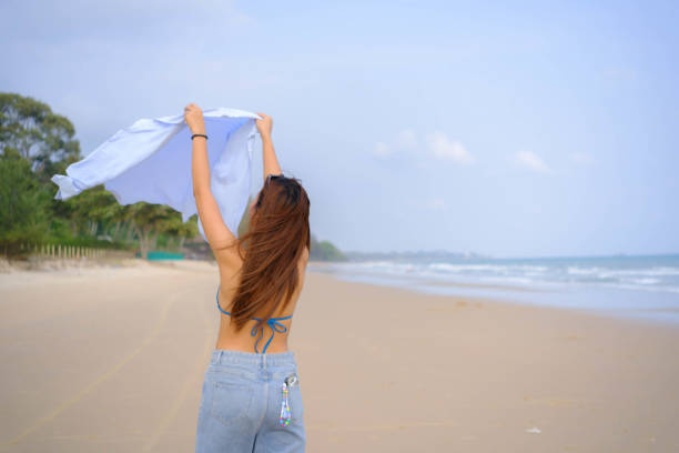 Beautiful Asian model wearing a hat, swimsuit and posing on the beach.