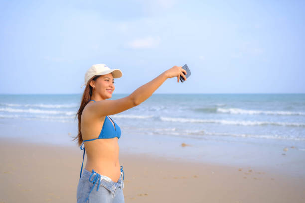 istock Beautiful Asian model wearing a hat, swimsuit and posing on the beach. 2099288416