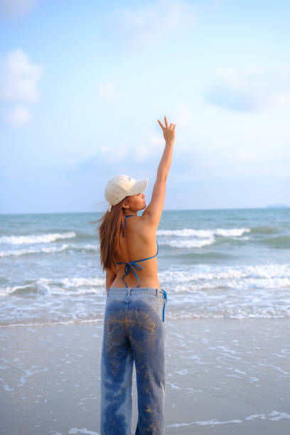 A young woman enjoys an empty beautiful beach with sand and blue sky in Porto, Portugal.