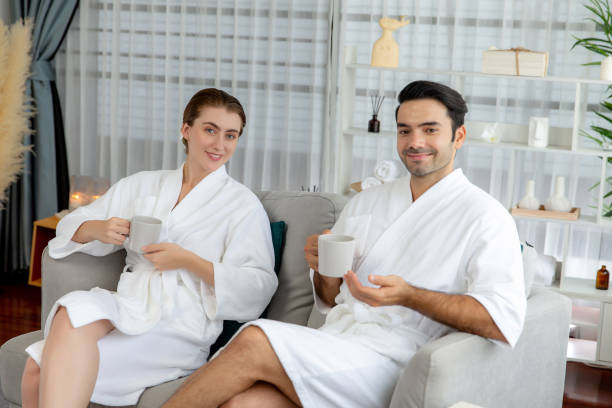 istock Couple wearing bathrobe relaxing with drinks in luxurious hotel spa. Quiescent 2099301273