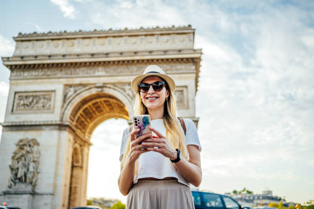 istock Woman using phone in front of the famous Arc de Triomphe 2099309368