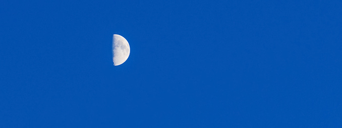 Small moon over blue glowing sky background.The Moon illuminated by the Sun.Web banner.