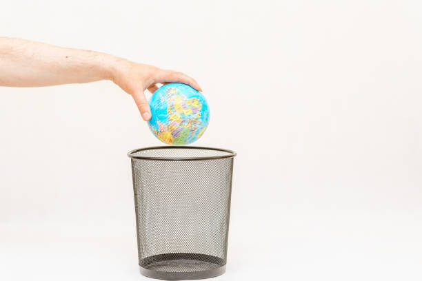 The world globe is thrown into the trash basket.White,gray background,selective focus,copy space.