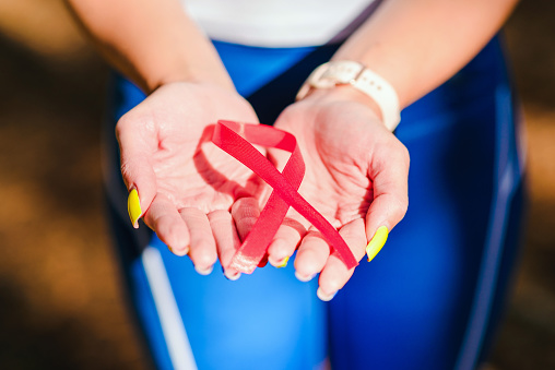 AIDS awareness.Caucasian woman hold red ribbon.Blurred background.World AIDS day concept.