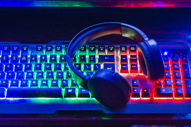 istock Pro gaming illuminated desk, headset, keyboard, computer neon lights. Cyber sport equipment laying on desktop, ready for online video gaming.Dark shot. 2099352153