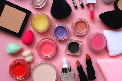 Various colorful beauty products on bright pink background. Top view.
