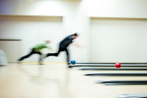 Defocussed shot of an amateur sportsmen playing bowling with the focus on the bowling balls.