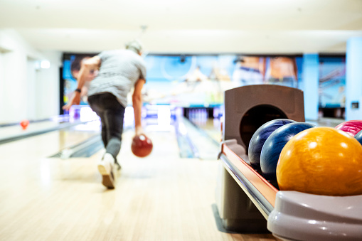 Defocussed shot of an amateur sportsman playing bowling with the focus on the bowling balls.