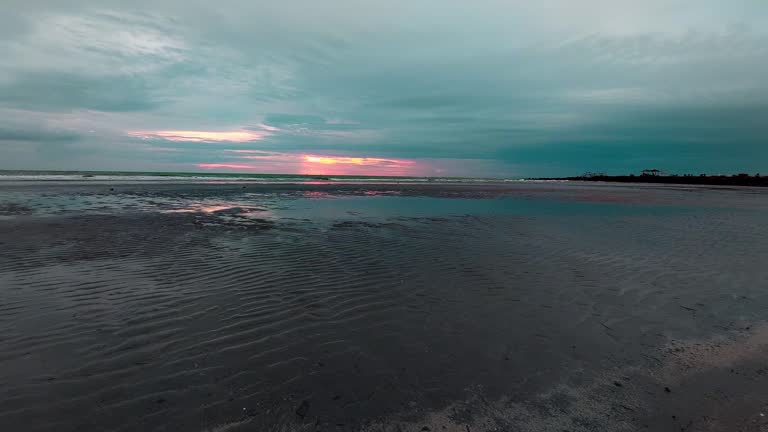 Hypnotic ambient motion of waves and currents on a wide shore during low tide. Dark moody cinematic scene