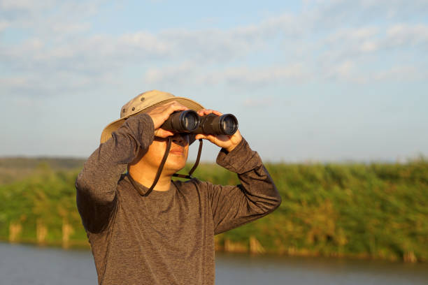 istock Asian man uses binoculars to observe local birds along a river. 2099393217