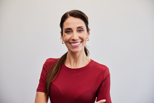 Portrait of a mature businesswoman smiling while standing with her arms crossed in front of a red wall in an office