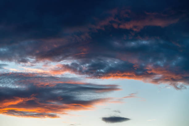 Sunset sky with dark clouds lit by orange hues, perfect for dramatic moods