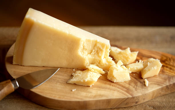Grana Padano cheese on cutting board Parmigiano Reggiano cheese on wooden board. Parmesan cheese on cutting board grana padano stock pictures, royalty-free photos & images