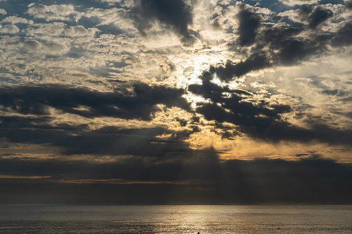 Sunset over Black Sea. Close-up. Beautiful multicolored clouds. Sea water glows in rays of setting sun. Atmosphere of tranquility and relaxation. Spring evening in Adler.