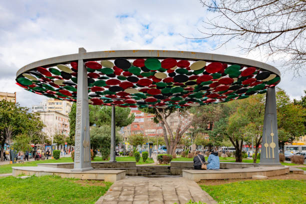 Tirana, Albania. 12 March 2024. Two people sit at the Friendship Monument in Tirana