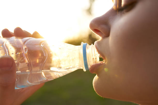 istock woman drinks water from a plastic bottle outdoors in summer close-up 2099454084