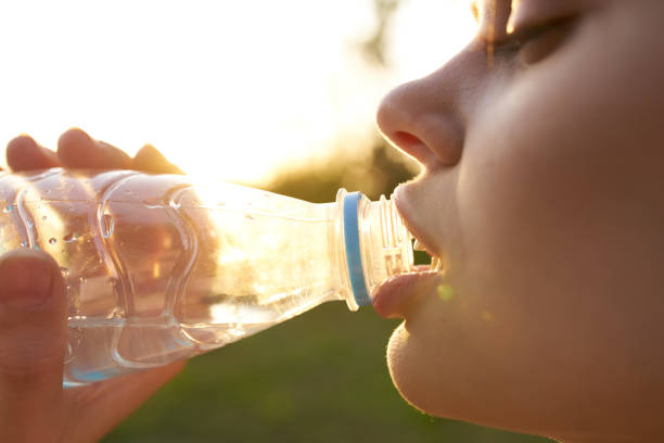 istock woman drinks water from a plastic bottle outdoors in summer close-up 2099456264