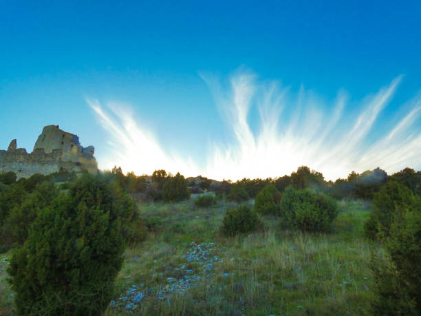 Photo of a magnificent blue sky with frayed clouds which embellish the landscape with the castle of Queen Jeanne next to it. This photo was taken at Eyguieres in the Alpilles in Provence in France.