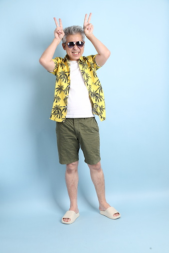 HAPPY SONGKRAN DAY. Asian tourist senior man in summer clothing with gesture of  Counting number isolated on blue background. Songkran festival. Thai New Year's Day.