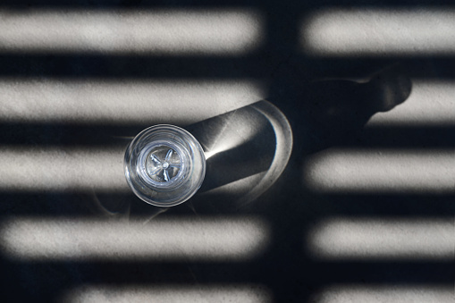 creative, minimalistic, elegant view from above of a bottle of water on a shade and dark ground