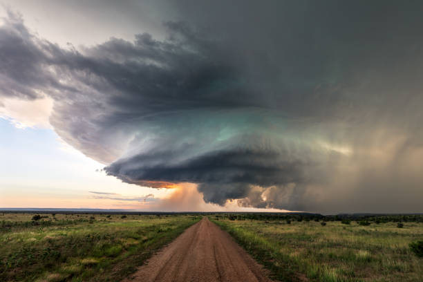 Dirt road leading to supercell storm clouds on the horizon at sunset near Kim, Colorado, USA.
