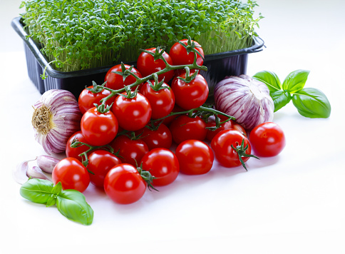 Cherry tomatoes and fresh lettuce and basil on a white background