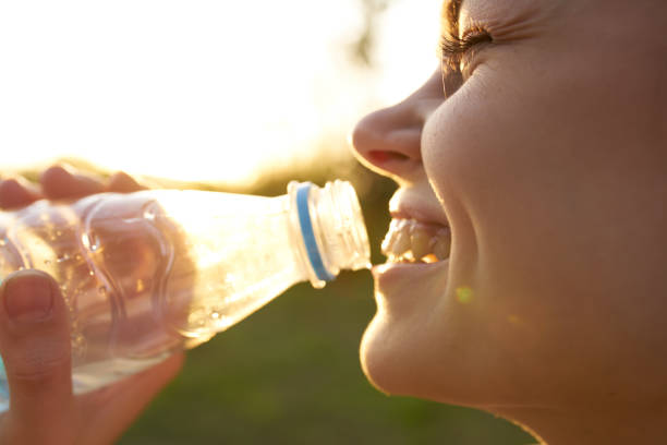 istock woman drinks water from a plastic bottle outdoors in summer 2099482953