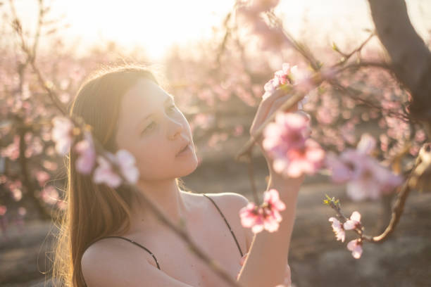 istock Woman looking at peach tree flowers 2099482955