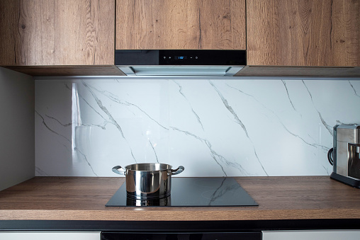 Stainless steel pot on an induction hob with built-in extractor hood